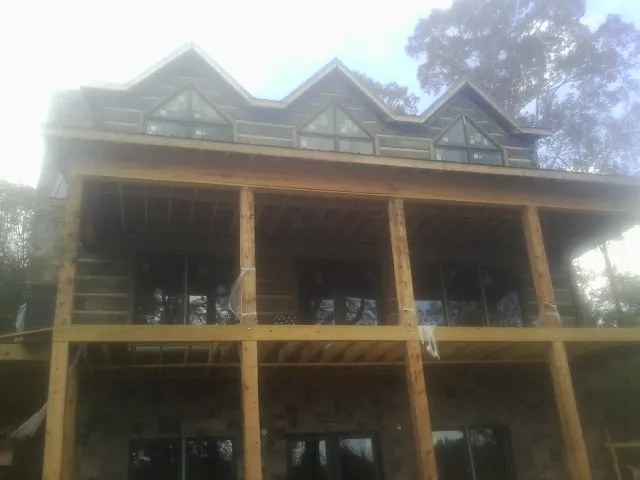 Dormers and porch framing on a large log home under construction — Roof Coating work by our crew in Glennville