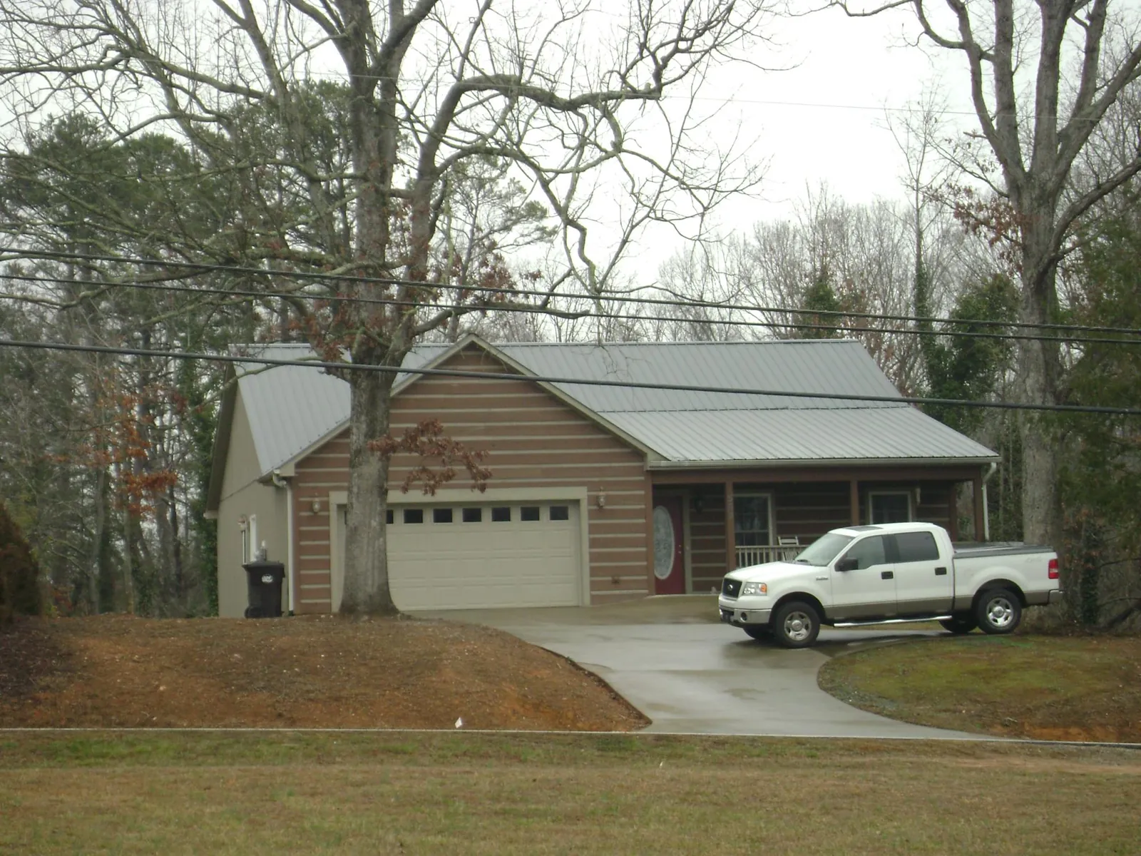 Gray metal roof on a log sided house with an attached two car garage in Glennville