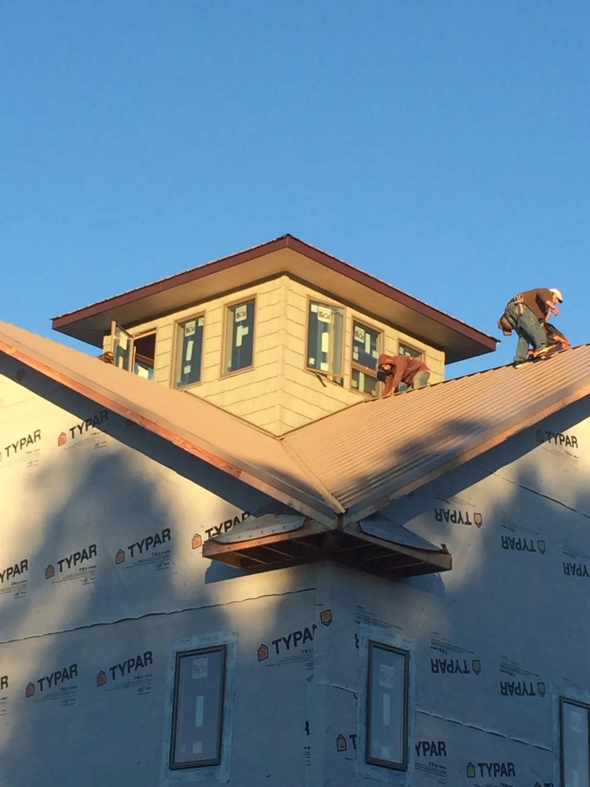 Roofers working around a rooftop cupola on a new metal roof at sunset — Roof Waterproofing in Glennville by Roofing Brothers